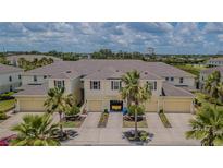 Inviting townhome exterior showcasing charming architecture, individual garages, and tropical landscaping under a partly cloudy sky at 10830 Verawood Dr, Riverview, FL 33579