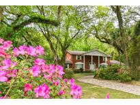 Beautiful two-story brick home with a circular driveway surrounded by lush azalea bushes and a manicured lawn at 11159 Cindy Dr, Brooksville, FL 34601