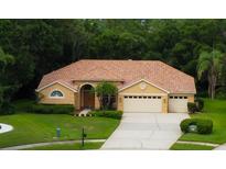 Charming single-story home with lush landscaping, tile roof, and a three-car garage at 1827 Foxboro Ct, Oldsmar, FL 34677
