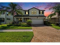 Beautiful two-story home featuring lush landscaping, brick driveway, and a welcoming facade at sunset at 19209 Long Lake Ranch Blvd, Lutz, FL 33558