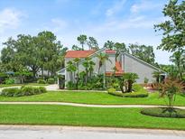 Striking modern home with red roof, lush tropical landscaping, and well-manicured lawn at 4118 Carrollwood Village Dr, Tampa, FL 33618