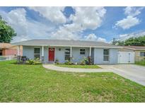 Charming single-story home with a red front door, lush lawn, and well-maintained landscaping at 4518 Ashmore Dr, Tampa, FL 33610