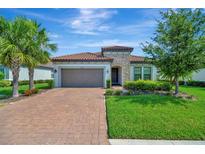 Charming home featuring a terracotta tile roof, brick paved drive, and a two-car garage at 5320 Morey Farms Loop, Palmetto, FL 34221