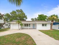 Charming single-story home with a well-manicured lawn, mature trees, and a freshly painted white exterior at 7571 Ridge Rd, Seminole, FL 33772