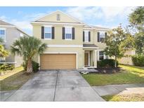 Inviting two-story home featuring a well-manicured lawn, attached garage, and neutral-toned exterior at 11539 Tangle Branch Ln, Gibsonton, FL 33534