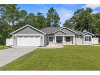 Charming single-story home with a manicured lawn, gray siding, and an attached two-car garage at 12333 Harris Hawk Rd, Weeki Wachee, FL 34614