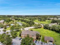 Beautiful aerial view of property with pond, lush green landscaping, and parking at 36243 Lake Chase Blvd # 102, Zephyrhills, FL 33541