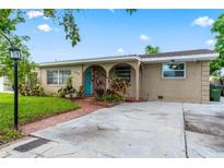 Charming single-story home with a well-manicured lawn, arched entry, and inviting turquoise front door at 3909 W Lemon St, Tampa, FL 33609