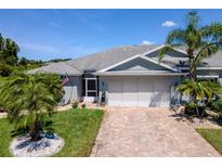 Charming single-story home with a brick driveway, an attached two-car garage, and beautiful tropical landscaping at 717 Manchester Woods Dr # 717, Sun City Center, FL 33573
