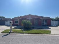 Charming single-story home features a red facade, decorative pillars, well-manicured lawn, and a concrete driveway at 7321 W Pocahontas Ave, Tampa, FL 33634