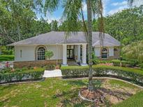 Charming home featuring a manicured front yard with lush landscaping and a welcoming entrance with stately columns at 8711 Crescent Forest Blvd, New Port Richey, FL 34654