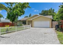 Charming single-story home with a brick driveway, white picket fence, and well-maintained landscaping at 9041 58Th N St, Pinellas Park, FL 33782