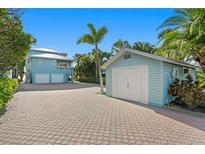 Charming blue house with a two-car garage and an additional single-car garage, surrounded by lush greenery at 20060 Gulf Blvd, Indian Shores, FL 33785