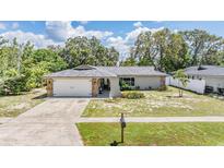 Charming single-story home with stone accents, mature trees, and a well-manicured front yard at 1403 Tallahassee Dr, Tarpon Springs, FL 34689