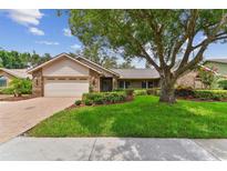 Charming single-story home with well-manicured lawn, mature trees, and brick-paved driveway leading to a two-car garage at 1810 Tamerlane Pl, Brandon, FL 33510