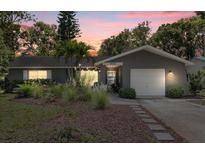 Charming single-story home with lush landscaping, a garage, and a welcoming entrance at dusk at 2850 Doone Cir, Palm Harbor, FL 34684