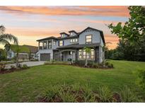 Stunning two-story home with a lush green lawn and beautifully landscaped flowerbeds at sunset at 2903 Cordoba Ranch Blvd, Lutz, FL 33559