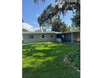 Charming single-story home featuring a well-maintained lawn and covered carport, shaded by mature trees at 3111 S Canal Dr, Palm Harbor, FL 34684