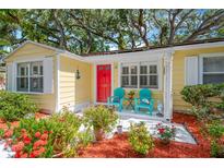 Charming home featuring a vibrant red door, colorful chairs, and lush landscaping for a welcoming entrance at 3129 W Villa Rosa St, Tampa, FL 33611