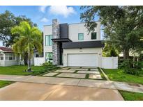 Modern two-story home with a stone accent and large garage, complemented by a lush green lawn and landscaping at 5816 S 3Rd St, Tampa, FL 33611