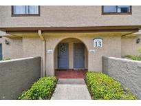 Charming condo entrance featuring a welcoming archway, gray doors, and lush green landscaping at 6262 142Nd N Ave # 1302, Clearwater, FL 33760