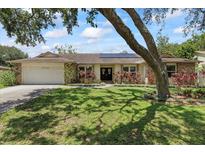 Charming single-story home featuring lush landscaping, brick accents, and solar panels for energy efficiency at 6706 Dunes Ln, Temple Terrace, FL 33617