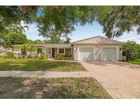 Charming single-story home with lush landscaping, brick driveway, and a two-car garage at 8010 Par N Ave, St Petersburg, FL 33710