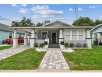 Charming home featuring a quaint front porch, freshly painted exterior, and beautifully manicured landscaping at 904 E Hamilton Ave, Tampa, FL 33604