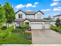 Beautiful two-story home featuring a three-car garage, lush landscaping, and a welcoming front porch with an American flag at 11828 Ranchers Gap Dr, Odessa, FL 33556