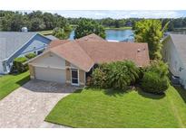 Charming single-story home with a brick driveway, attached garage, and lush landscaping overlooking the serene lake at 12038 Steppingstone Blvd, Tampa, FL 33635