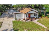 Charming bungalow with a red front door, gravel driveway and detached garage at 1217 E 29Th Ave, Tampa, FL 33605