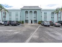 Three story condo building with light blue painted facade, arched entry and ample parking at 1706 Belleair Forest Dr # 146, Belleair, FL 33756