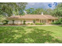 Inviting single-story home with a lush green lawn, mature trees, and decorative stone accents on the facade at 18110 30Th St, Lutz, FL 33559