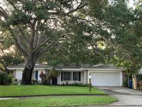 Charming single-story home with a well-manicured lawn and mature trees providing shade at 1861 Harmony Dr, Clearwater, FL 33756