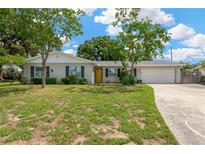 Charming home featuring a well-manicured front lawn, mature trees, and an inviting yellow front door at 2325 W Knollwood Pl, Tampa, FL 33604