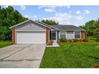 Charming single-story home with gray siding, brick accents, and an attached two-car garage at 2868 Denmarsh Ct, Palm Harbor, FL 34684
