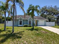 Charming single-story home with arched windows, yellow door, attached garage, and well-maintained lawn and palm trees at 4707 Barrett Ct, Tampa, FL 33617