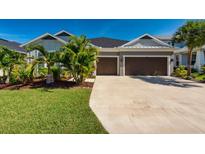 Charming home featuring a two-car garage, well-manicured lawn, and tropical landscaping at 4906 Los Robles Ct, Palmetto, FL 34221