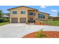 Inviting tan two-story home featuring a two-car garage, balcony, and well-manicured landscaping at 6780 Greenbrier Dr, Seminole, FL 33777