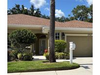 Charming single-story home with a well-manicured lawn, lush landscaping, and an attached two-car garage at 12747 Aston Creek Dr, Tampa, FL 33626