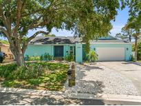 Charming turquoise home featuring a well-manicured lawn, mature trees, and a white gravel driveway at 14030 79Th Ave, Seminole, FL 33776