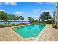 Beautiful waterfront pool with brick trim and lush landscaping under a sunny sky at 1531 75Th Ne Cir, St Petersburg, FL 33702