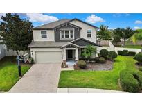 Inviting two-story home with a well-manicured lawn and brick driveway, featuring an attached two-car garage at 1669 Feather Grass Loop, Lutz, FL 33558