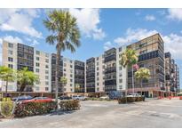 Exterior view of a multi-story condo building with balconies, landscaping, and a parking lot with palm trees at 2901 26Th W St # 815, Bradenton, FL 34205