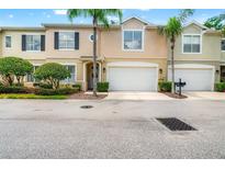 Charming townhome featuring a two-car garage, landscaped front yard, and stately palm trees at 3519 Heards Ferry Dr, Tampa, FL 33618