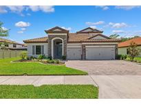 Charming front exterior features a three-car garage and tiled roof, situated on a well-manicured lawn at 3999 Burdick Loop, Odessa, FL 33556