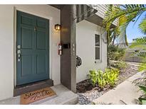 Inviting teal front door with a 'Stay awhile' welcome mat and lush tropical landscaping around the entrance at 441 75Th N Ave, St Petersburg, FL 33702