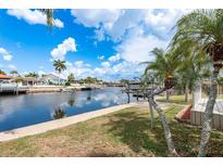 Scenic waterfront view featuring a private dock and lush tropical landscaping under a sunny sky at 5008 Glenn Dr, New Port Richey, FL 34652