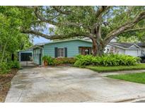 Charming home featuring a lovely turquoise exterior, beautiful landscaping, and mature trees in front at 8014 27Th N Ave, St Petersburg, FL 33710