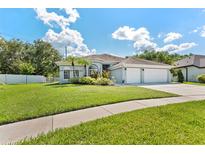 Charming single-story home with a lush lawn, mature landscaping, and a three-car garage, perfect for curb appeal at 12910 Vicksburg Dr, Tampa, FL 33625